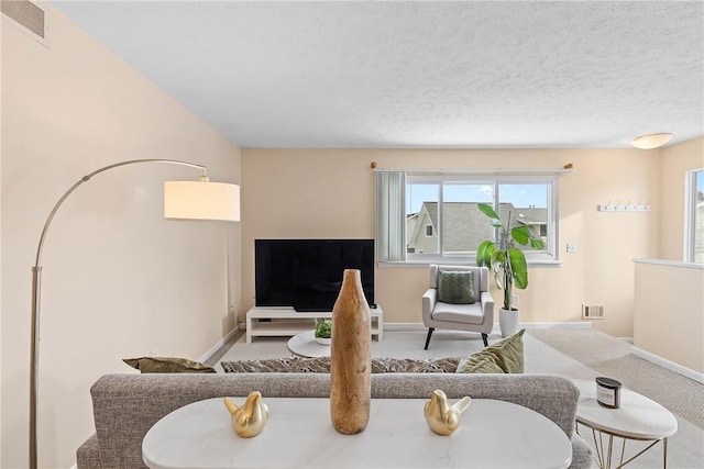 carpeted living room with baseboards, visible vents, and a textured ceiling