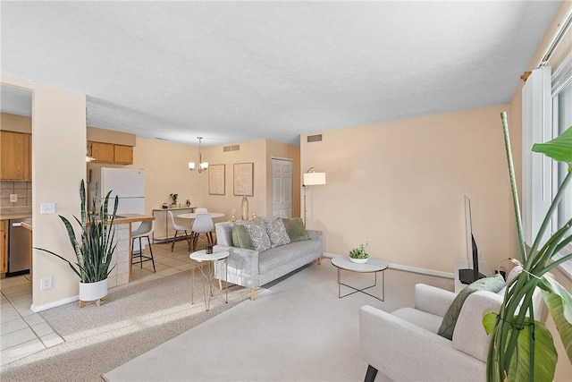 living room with light colored carpet, visible vents, a notable chandelier, and a textured ceiling