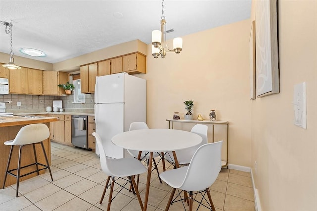 kitchen featuring white appliances, light brown cabinets, pendant lighting, and light countertops