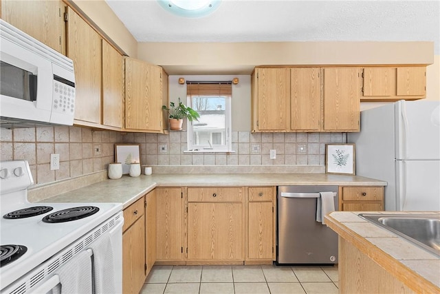 kitchen featuring tasteful backsplash, white appliances, light countertops, and light tile patterned floors