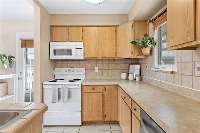 kitchen featuring light tile patterned floors, white appliances, light countertops, backsplash, and a wealth of natural light