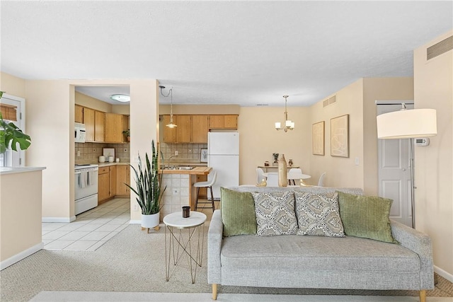 living area with baseboards, light tile patterned floors, visible vents, and an inviting chandelier