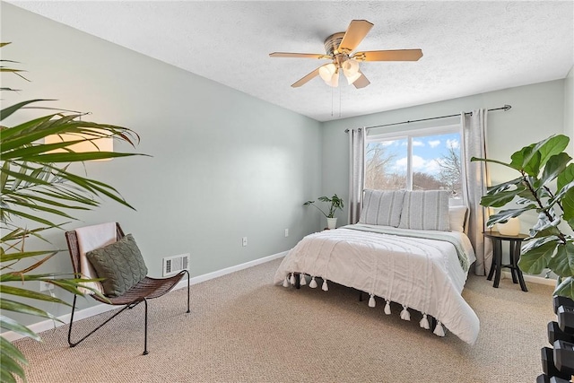 carpeted bedroom featuring a ceiling fan, visible vents, a textured ceiling, and baseboards