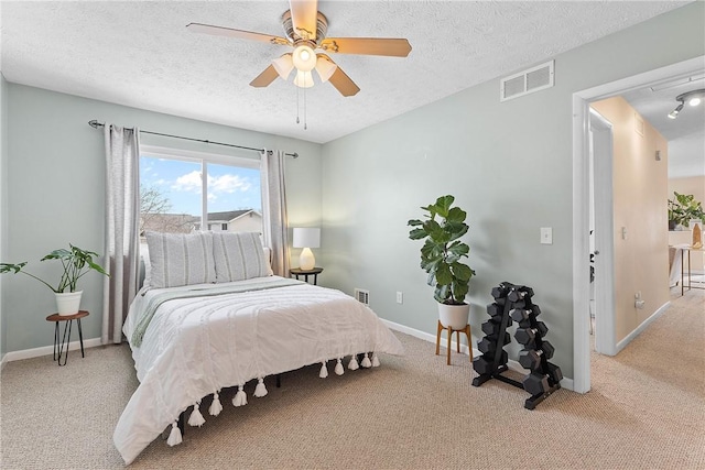 bedroom featuring baseboards, visible vents, a textured ceiling, and light colored carpet