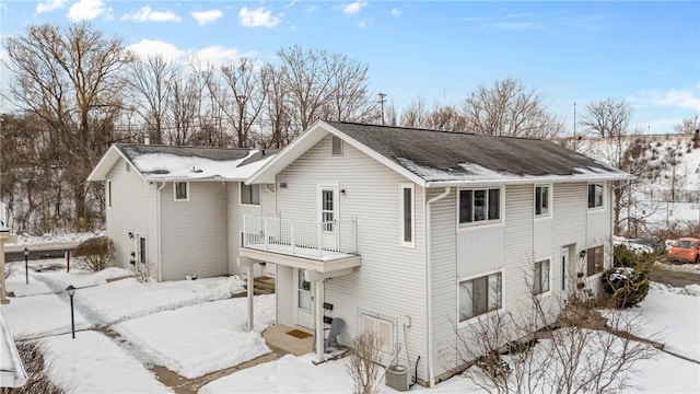 snow covered property featuring a balcony and central AC unit