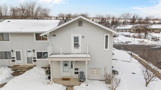 snow covered house featuring a balcony