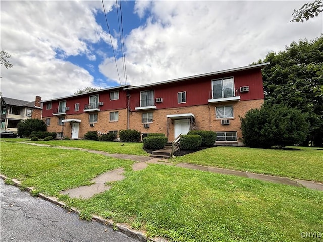 view of property featuring a front lawn and brick siding