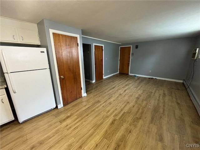 kitchen featuring light wood-style flooring, white cabinets, and freestanding refrigerator