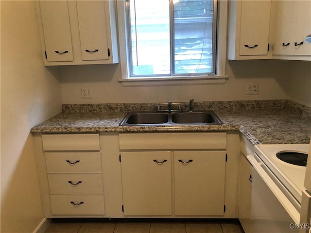 kitchen featuring baseboards, light tile patterned flooring, a sink, and white cabinets