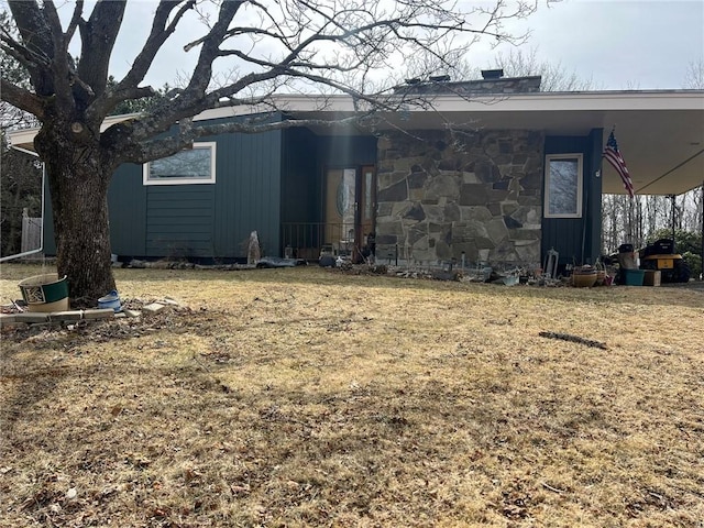 view of property exterior with a carport, stone siding, and a lawn