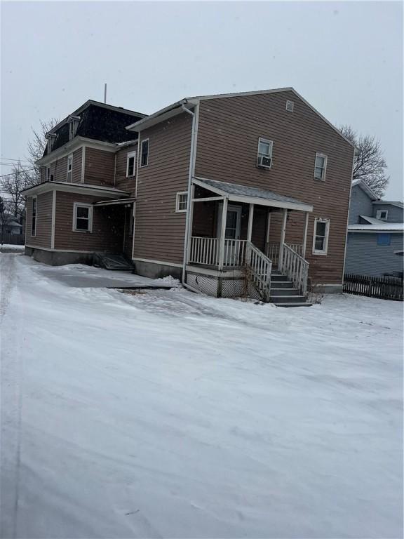 snow covered property with covered porch