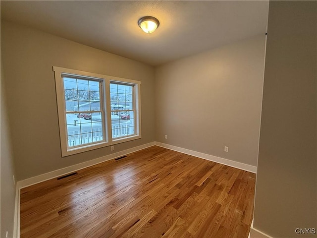 unfurnished room featuring light wood-type flooring, baseboards, and visible vents