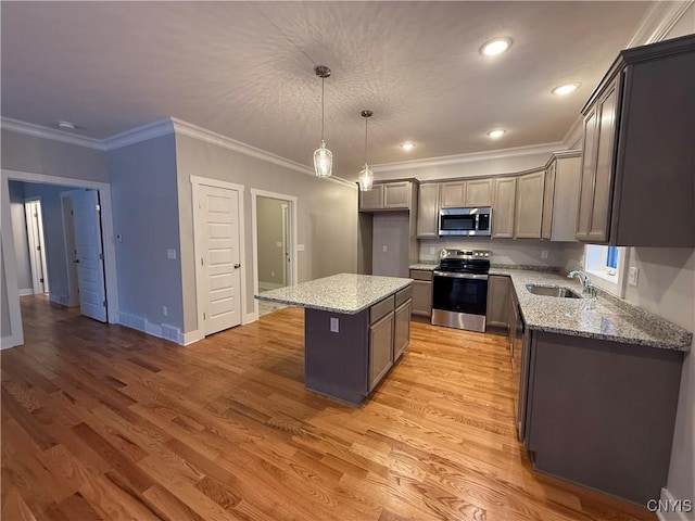 kitchen with a kitchen island, appliances with stainless steel finishes, light stone countertops, pendant lighting, and a sink