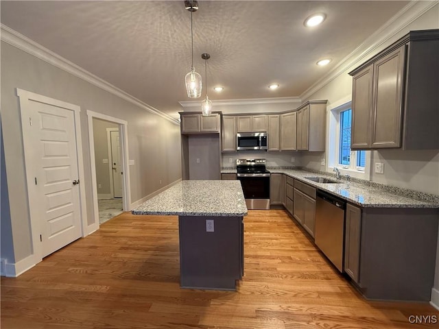 kitchen with decorative light fixtures, stainless steel appliances, a kitchen island, a sink, and light stone countertops