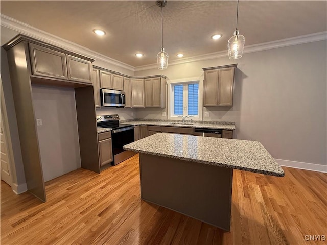 kitchen with a kitchen island, appliances with stainless steel finishes, light stone counters, light wood-style floors, and pendant lighting