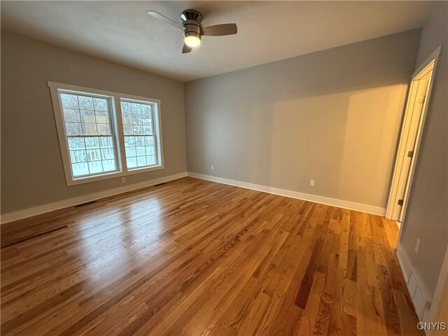 empty room featuring visible vents, light wood finished floors, a ceiling fan, and baseboards