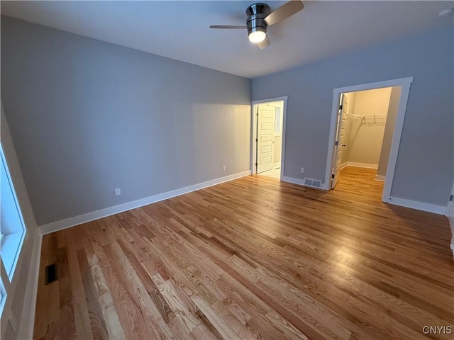 unfurnished bedroom with visible vents, light wood-style flooring, baseboards, and a spacious closet