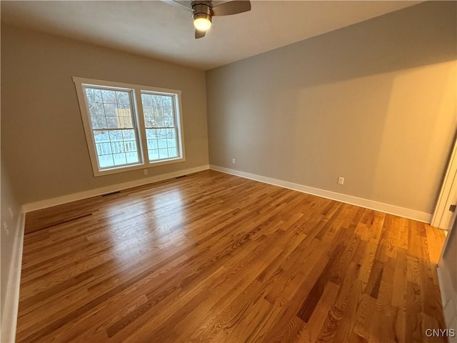 unfurnished room with ceiling fan, visible vents, light wood-style flooring, and baseboards