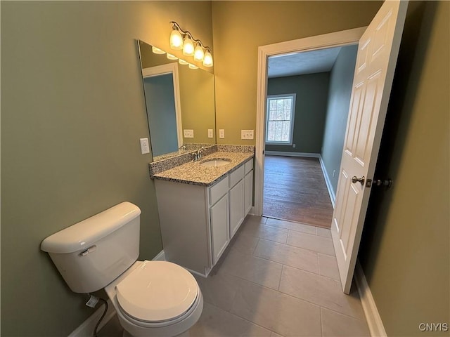 half bath with toilet, tile patterned flooring, baseboards, and vanity