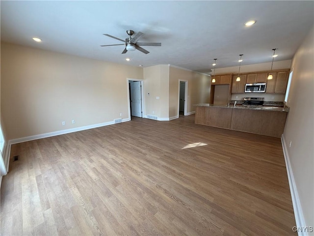 unfurnished living room with dark wood-style floors, visible vents, baseboards, and a ceiling fan