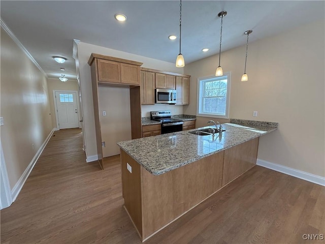 kitchen with light stone counters, decorative light fixtures, appliances with stainless steel finishes, a sink, and a peninsula