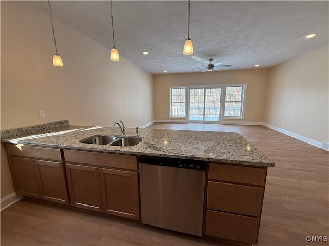 kitchen featuring open floor plan, a sink, hanging light fixtures, and stainless steel dishwasher