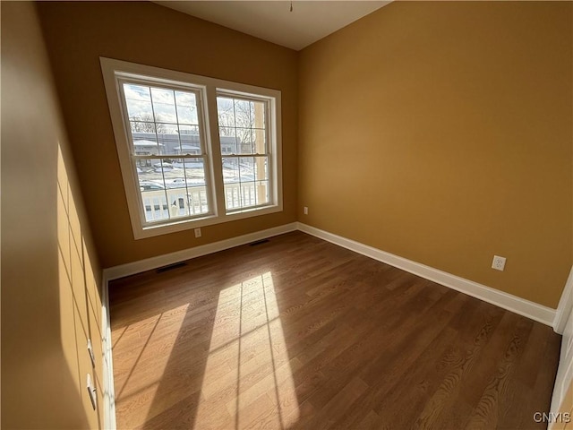 empty room with visible vents, baseboards, and wood finished floors