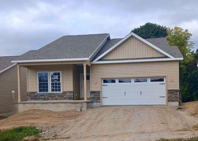 craftsman-style house featuring a garage, stone siding, driveway, and a porch