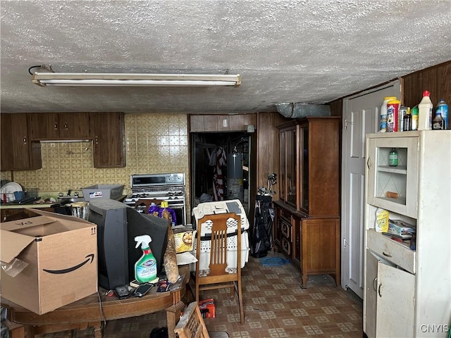 kitchen with wood walls, a textured ceiling, and tile patterned floors