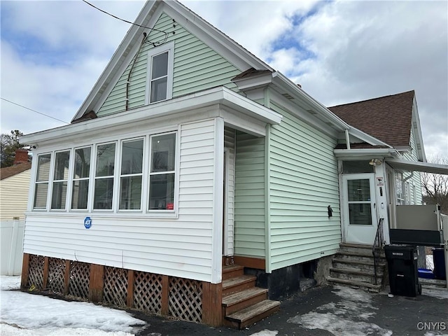 view of home's exterior with entry steps and a shingled roof