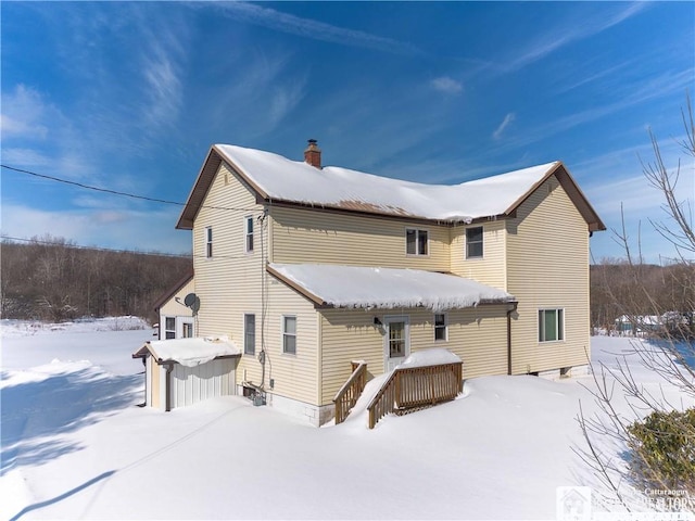 snow covered rear of property featuring a chimney