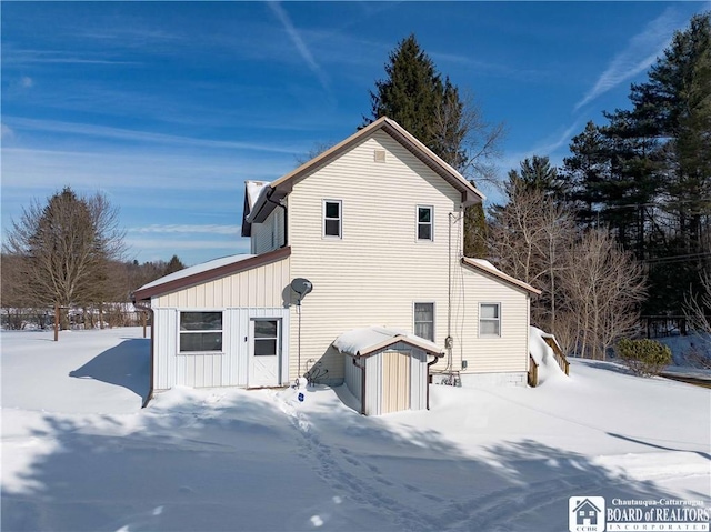 snow covered property with board and batten siding