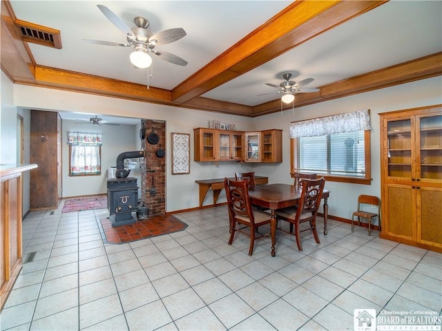 dining room featuring a wood stove, light tile patterned floors, baseboards, and a raised ceiling