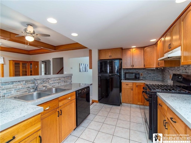 kitchen with light tile patterned flooring, under cabinet range hood, a sink, brown cabinets, and black appliances