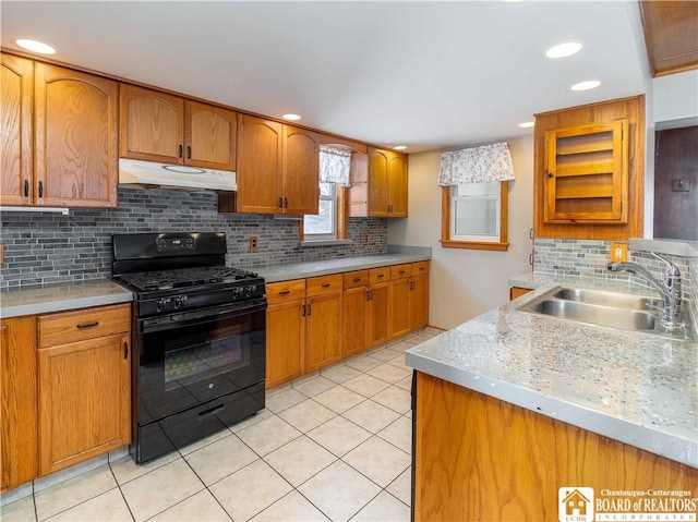 kitchen with light tile patterned floors, under cabinet range hood, a sink, light countertops, and black gas range oven