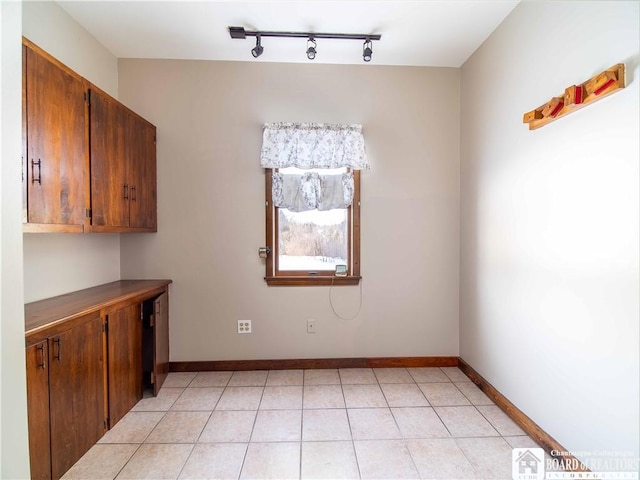 unfurnished dining area with light tile patterned flooring and baseboards