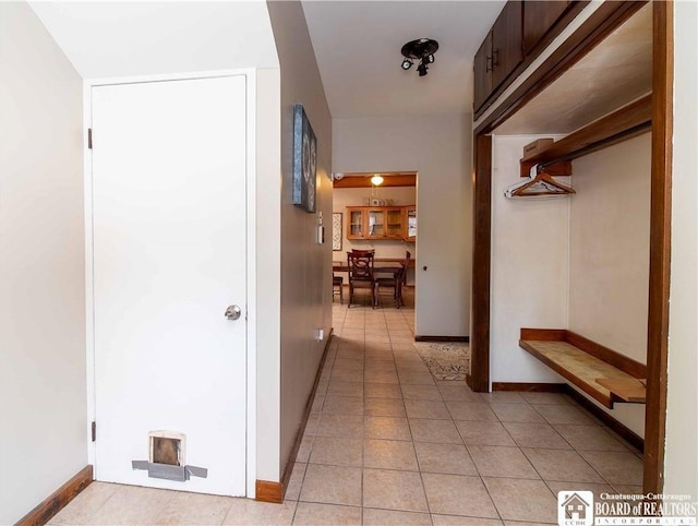 corridor with light tile patterned floors and baseboards