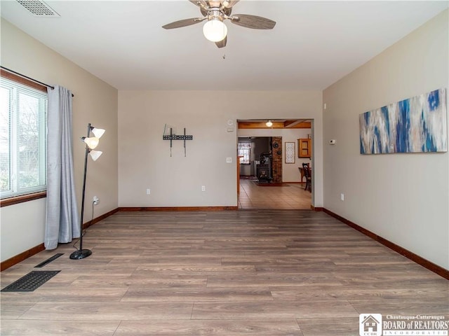 spare room with wood finished floors, visible vents, and baseboards