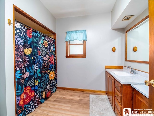 bathroom with baseboards, wood finished floors, and vanity