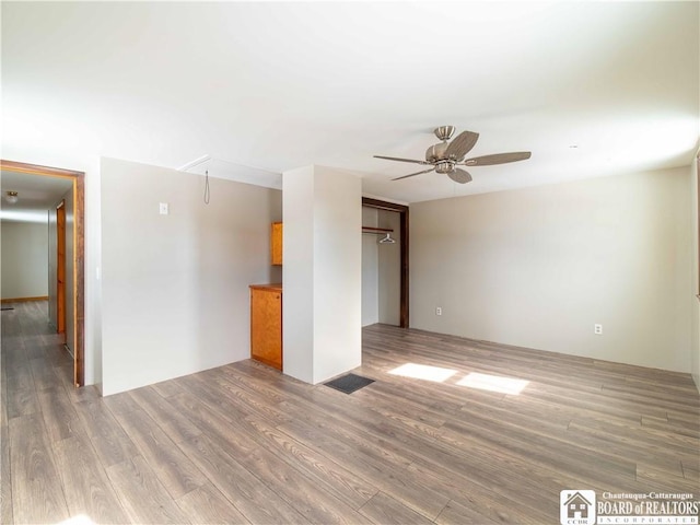 spare room with visible vents, attic access, a ceiling fan, and wood finished floors