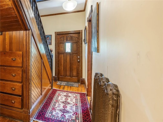 doorway with ornamental molding, stairs, and wood finished floors