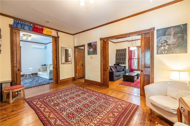 living room featuring a wall mounted AC, hardwood / wood-style flooring, baseboards, and ornamental molding