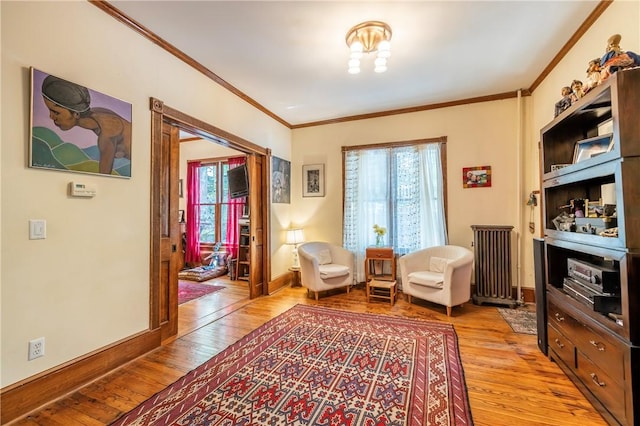 sitting room featuring light wood-style flooring, crown molding, and baseboards