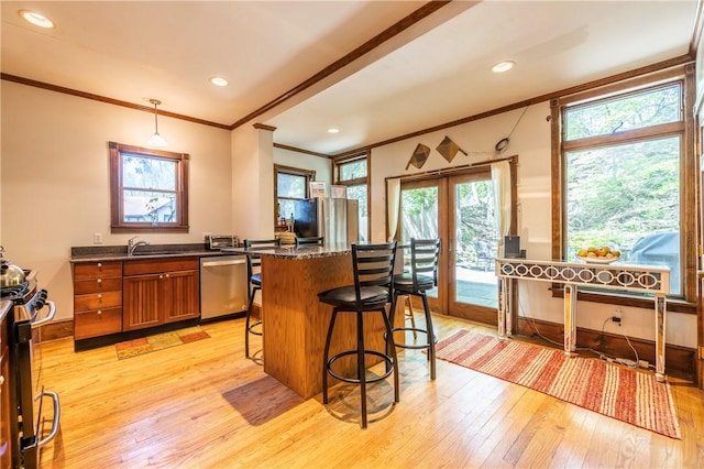 kitchen featuring a kitchen bar, light wood-style flooring, french doors, appliances with stainless steel finishes, and brown cabinetry