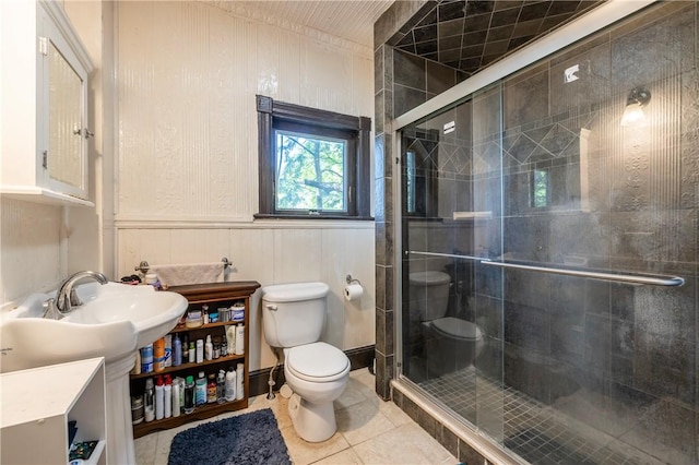 full bath featuring tile patterned flooring, a shower stall, toilet, and a wainscoted wall