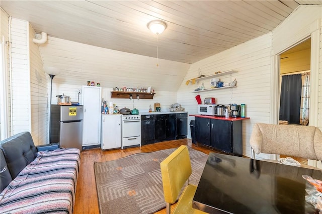 kitchen featuring open shelves, lofted ceiling, wood finished floors, and freestanding refrigerator