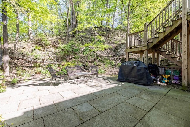 view of patio / terrace featuring stairs, a forest view, and a grill