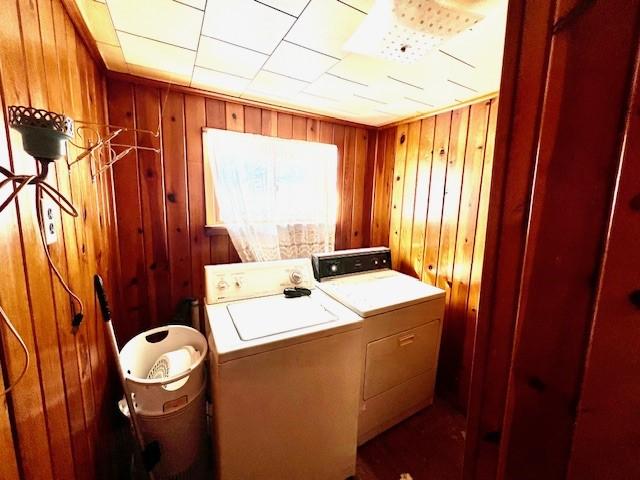 laundry area featuring laundry area, wood walls, and independent washer and dryer