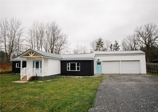 view of front facade featuring a front yard, metal roof, driveway, and an attached garage