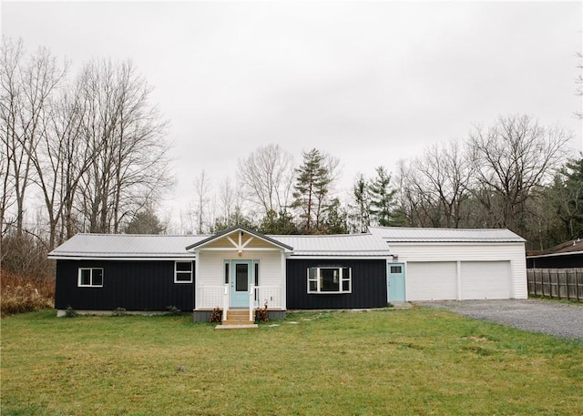 ranch-style home with a garage, metal roof, driveway, and a front lawn